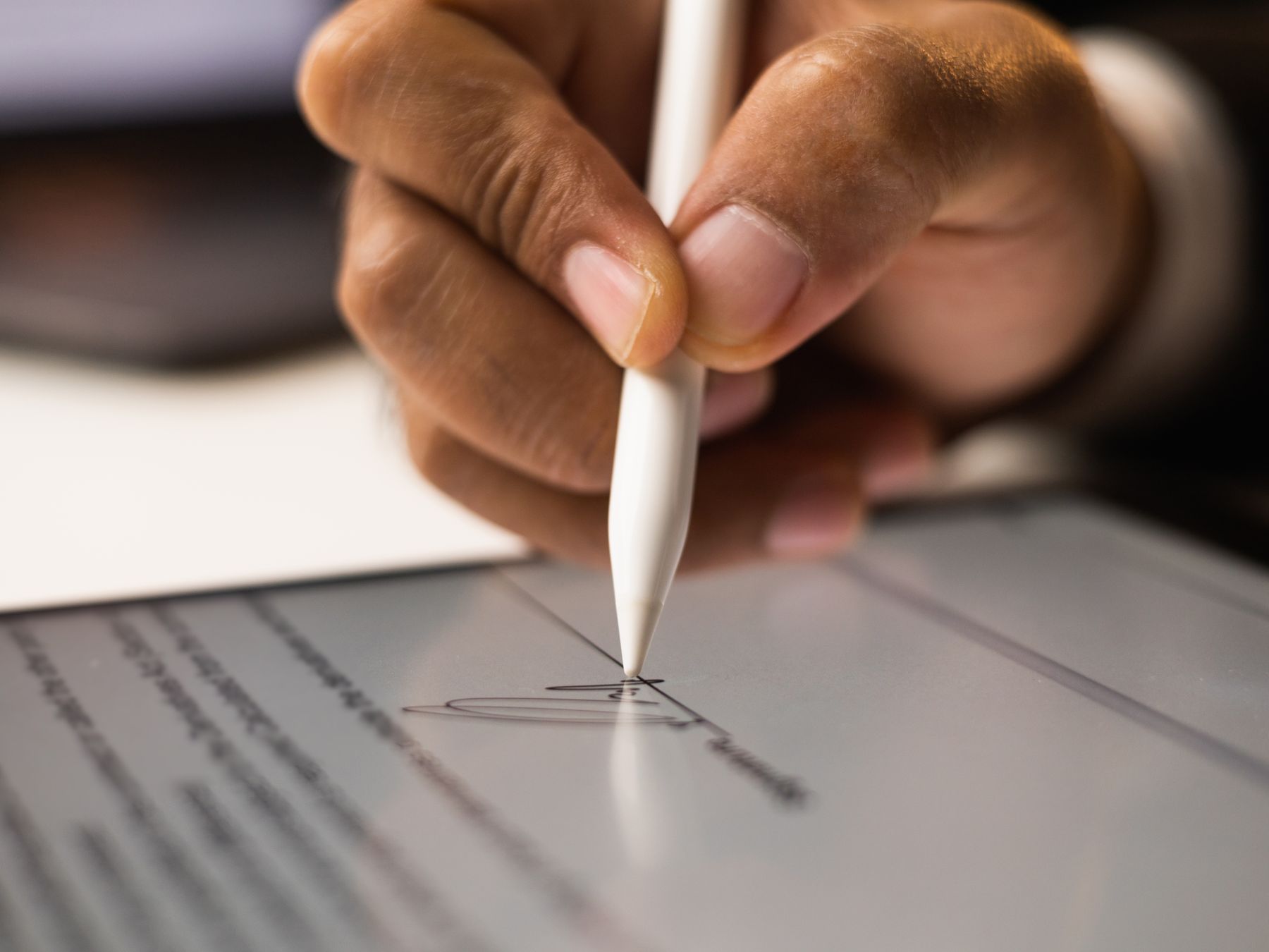 Mão assinando um contrato com caneta digital na tela de um tablet.