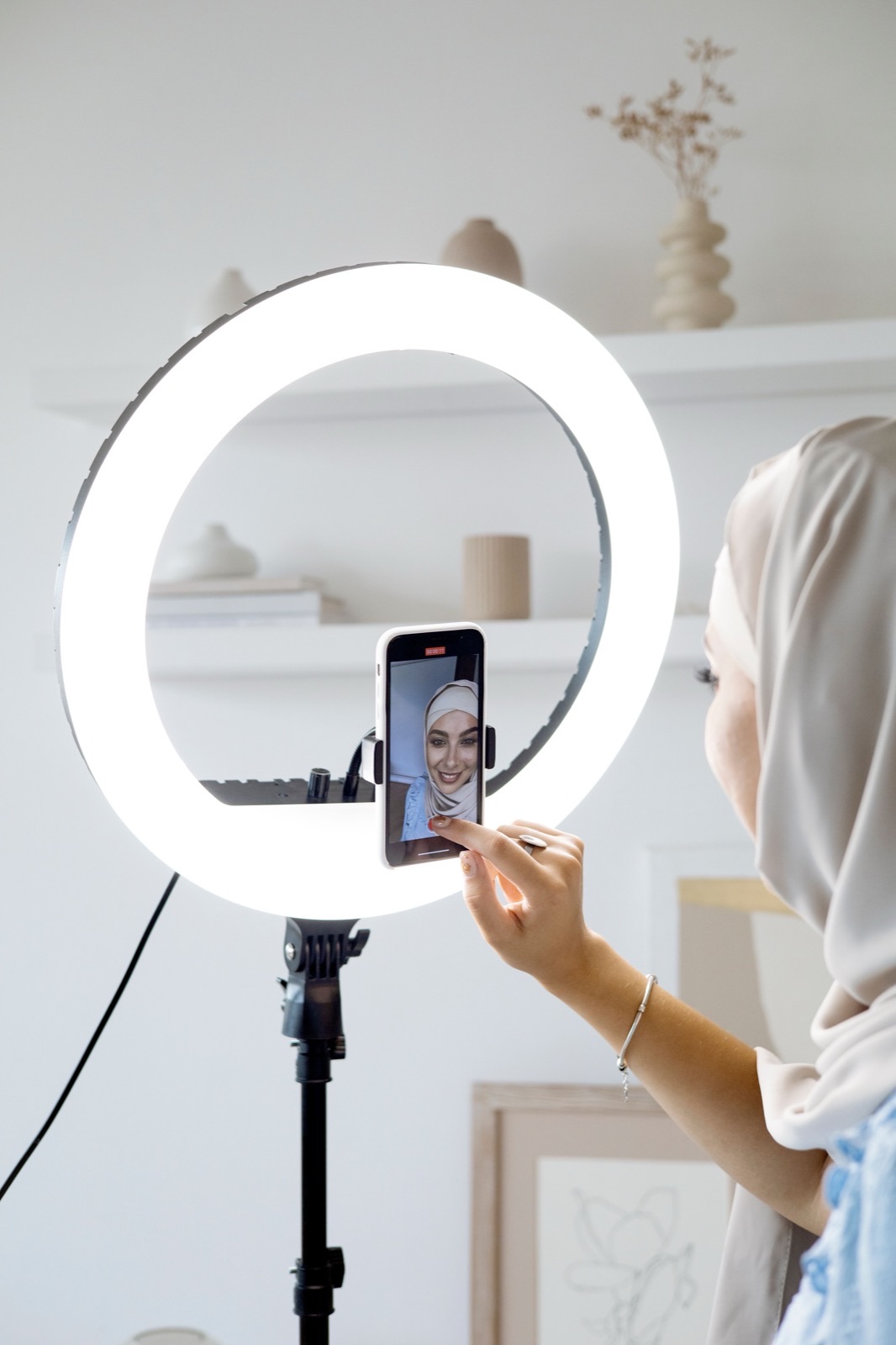Creator gravando um vídeo com o celular preso no meio de um ring light grande montado em tripé