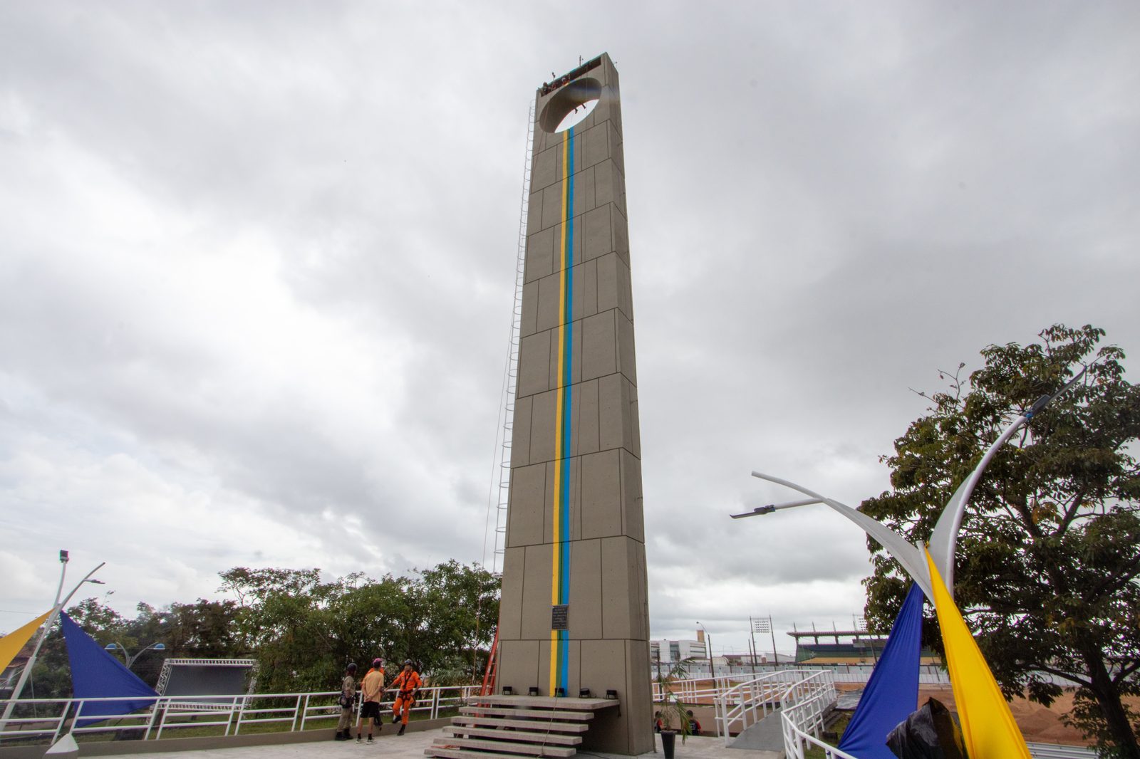 Obelisco do Marco Zero do Equador em Macapá visto de baixo, sob céu nublado, com a abertura circular no topo e uma linha azul e amarela pintada ao longo da fachada marcando a linha do Equador.