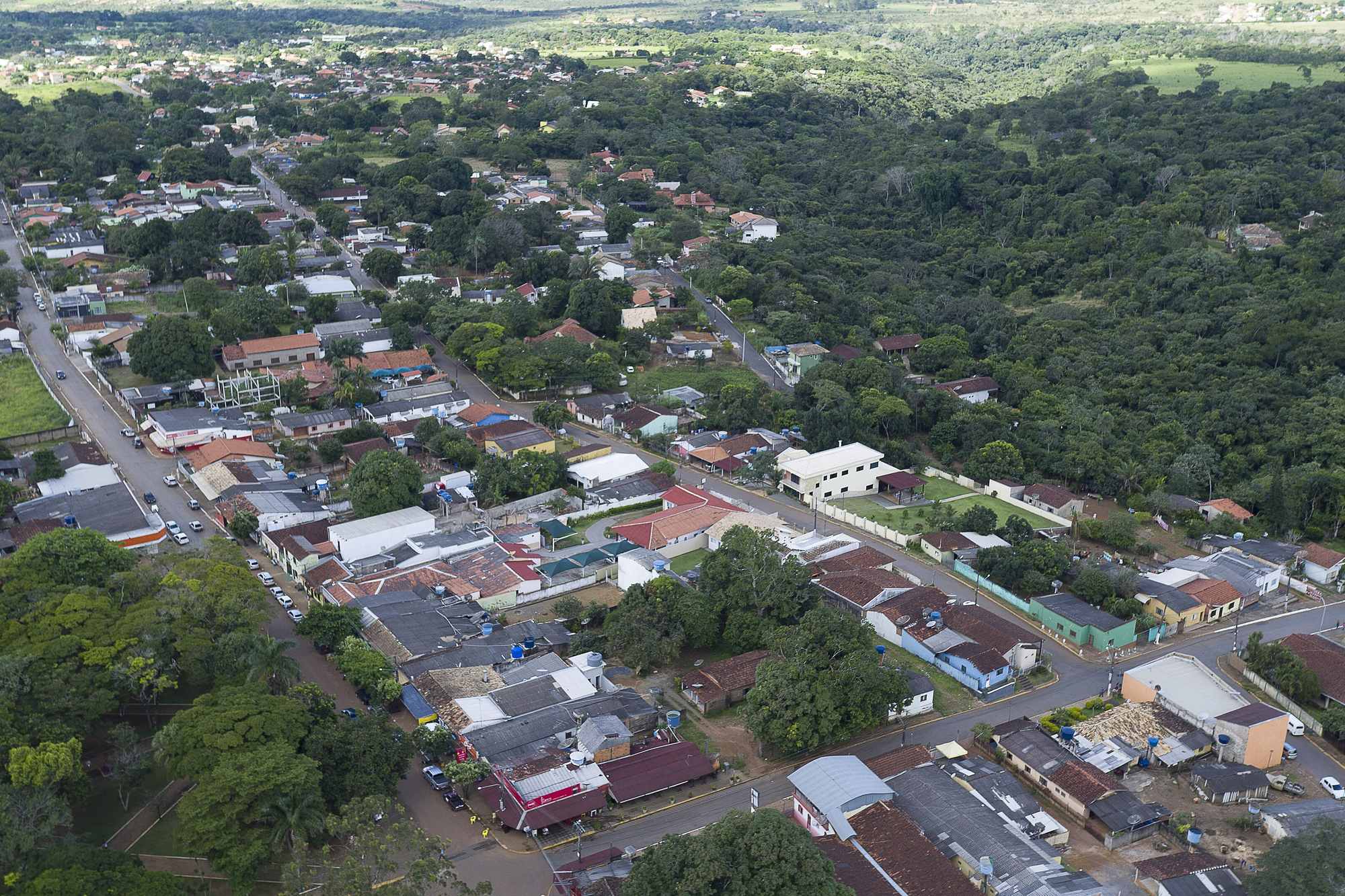 Vista aérea da cidade de Chapada dos Guimarães, com as ruas, as casas de telhado vermelho e o cerrado verde em volta.