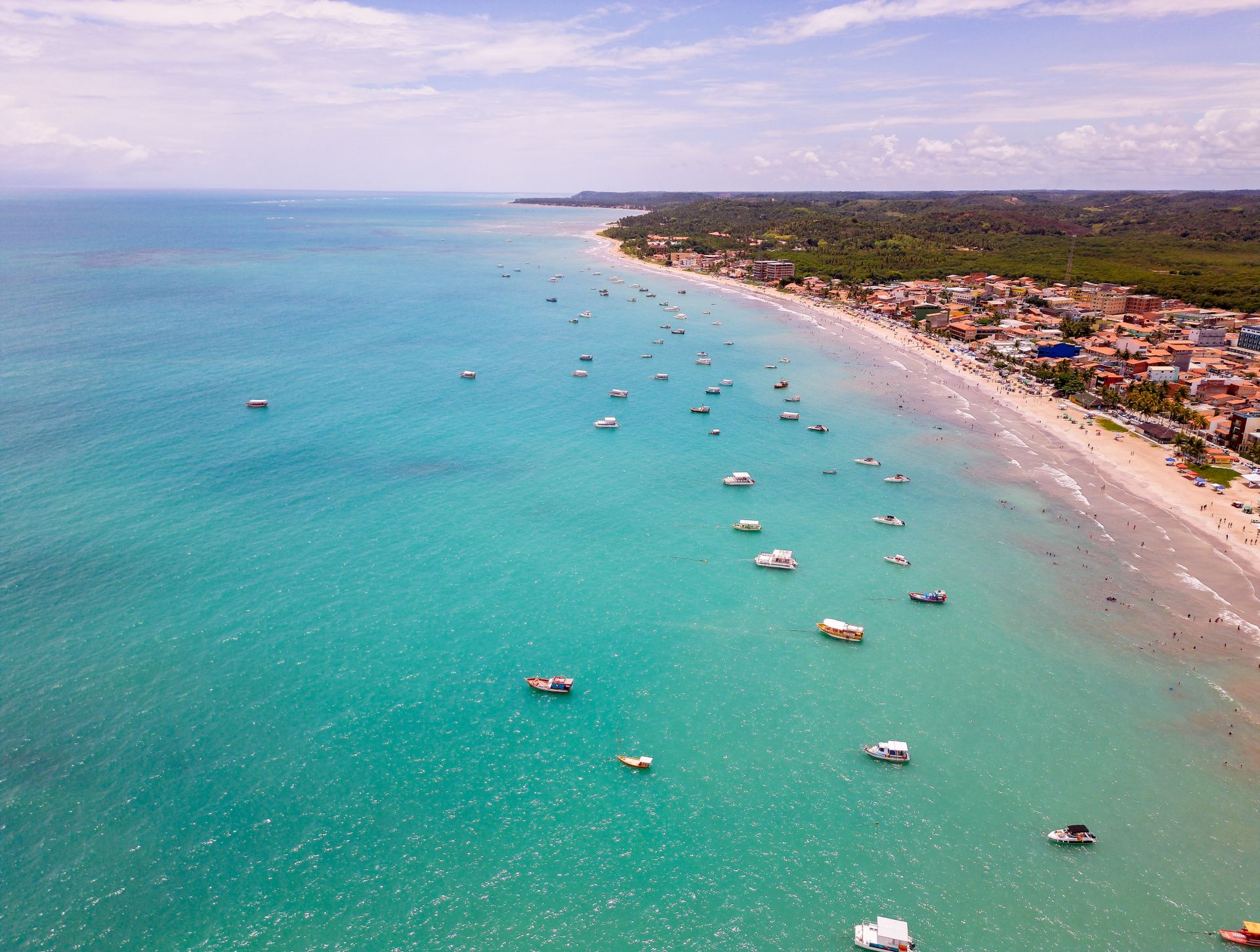 Vista aérea da praia de Maragogi com barcos ancorados em água turquesa perto da faixa de areia