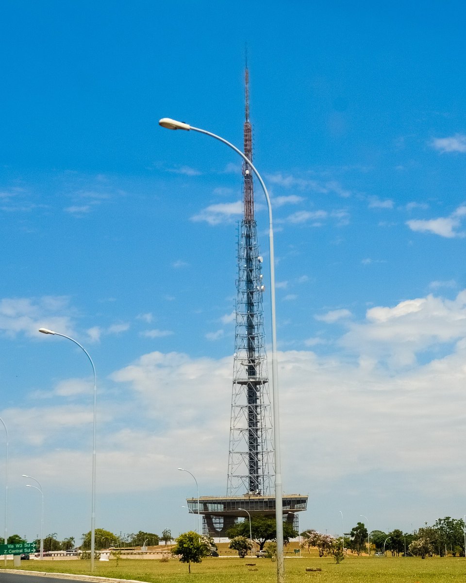 Torre de TV de Brasília vista do gramado do Eixo Monumental, com a estrutura de aço apontando para o céu azul.