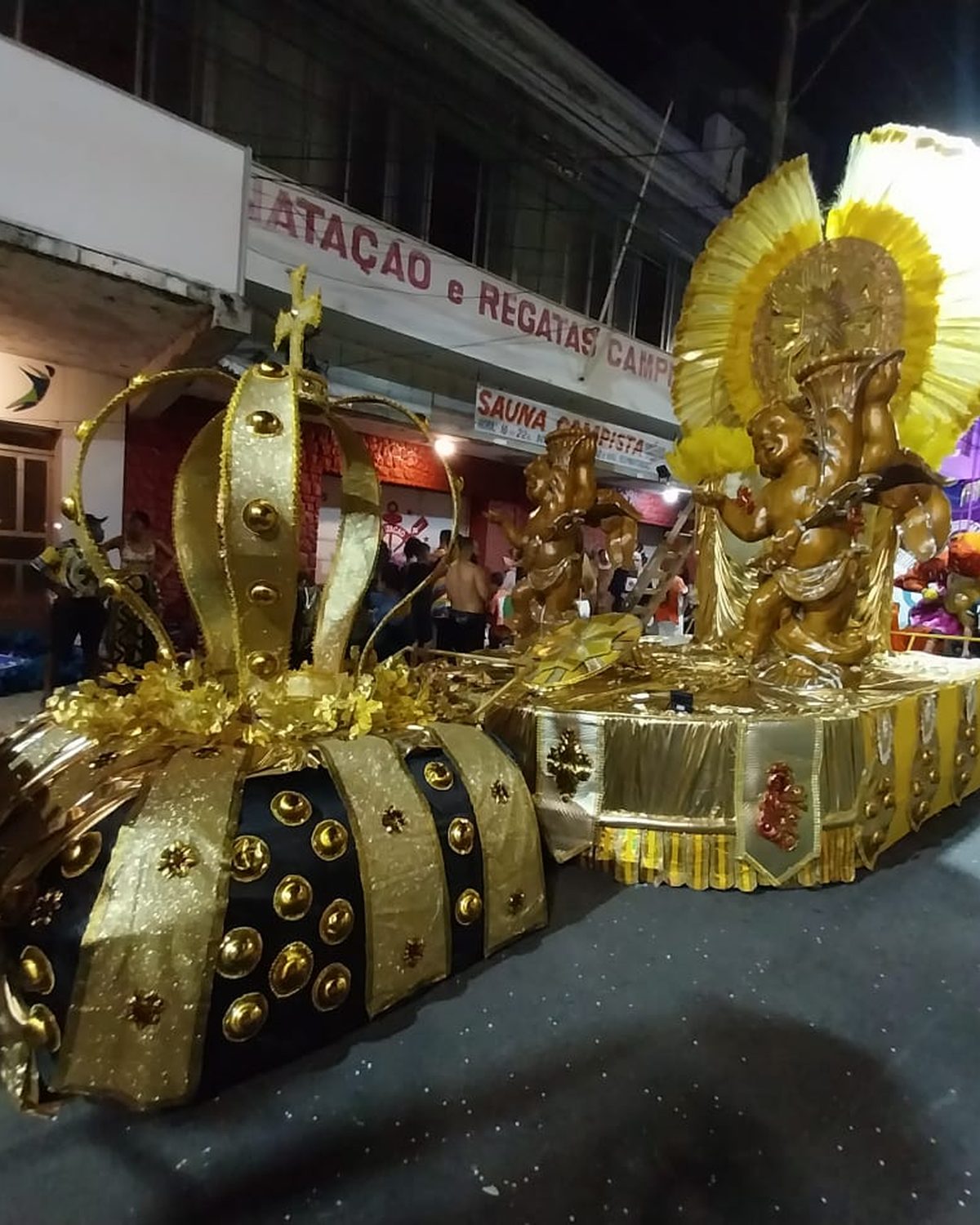 Carro alegórico de escola de samba numa rua de comércio de Campos dos Goytacazes.