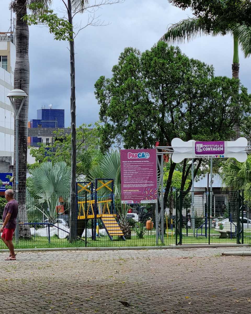 Praça arborizada no Novo Eldorado, em Contagem, com um homem caminhando.