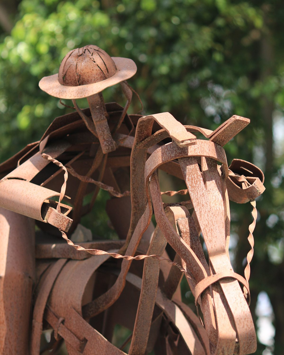 Escultura de metal de um vaqueiro montado a cavalo, com chapéu de couro, feita de chapas recortadas e cor de ferrugem, em Feira de Santana.