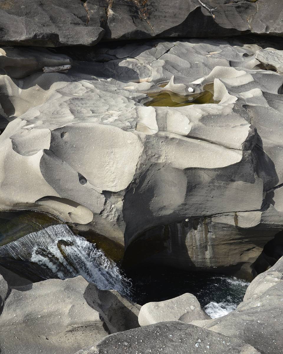 Vale da Lua, na Chapada dos Veadeiros, com as rochas cinzentas esculpidas pela água em curvas e buracos e o rio correndo entre elas.