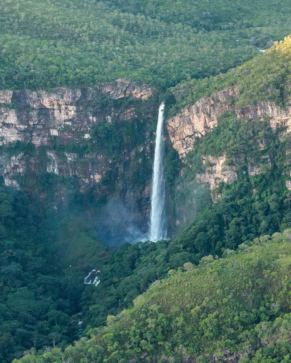 Salto do Itiquira, em Formosa, com a queda d'água fina e alta descendo o paredão de pedra no meio de um vale coberto de mata verde.