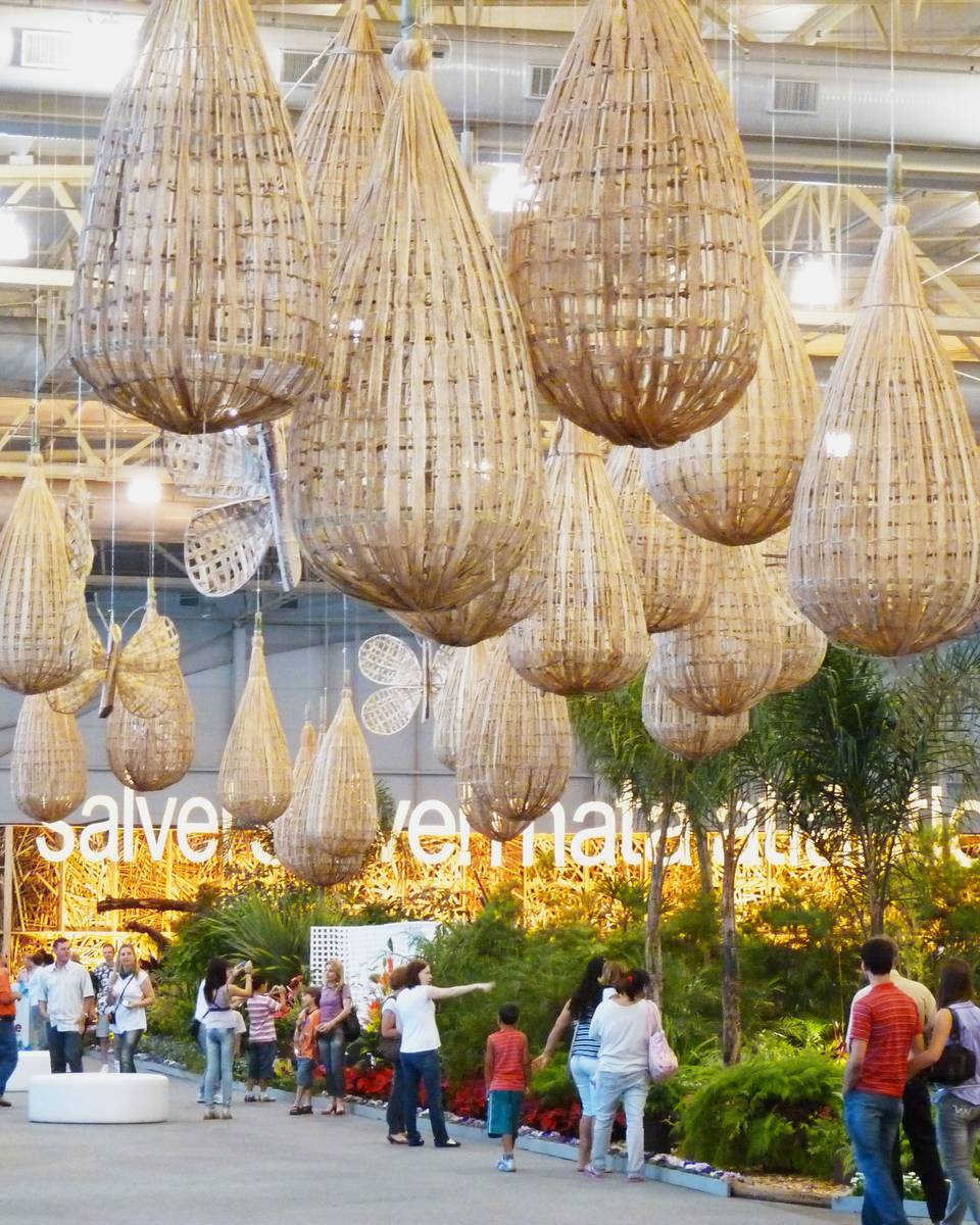 Visitantes na Festa das Flores, em Joinville, sob cestos de palha pendurados no teto.
