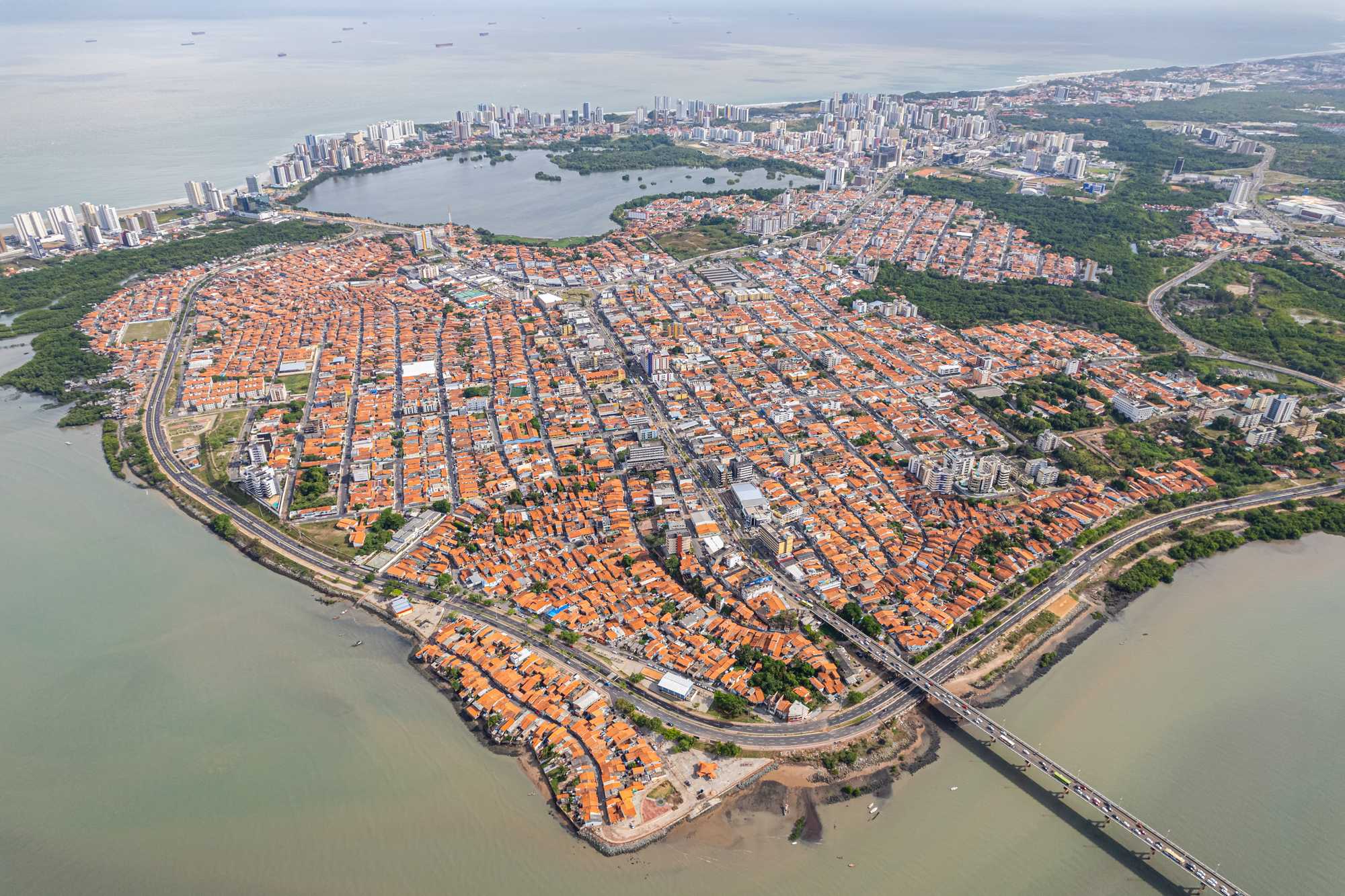Vista aérea da península do Centro Histórico de São Luís, com os telhados de telha vermelha do casario colonial, a ponte e as águas da baía ao redor