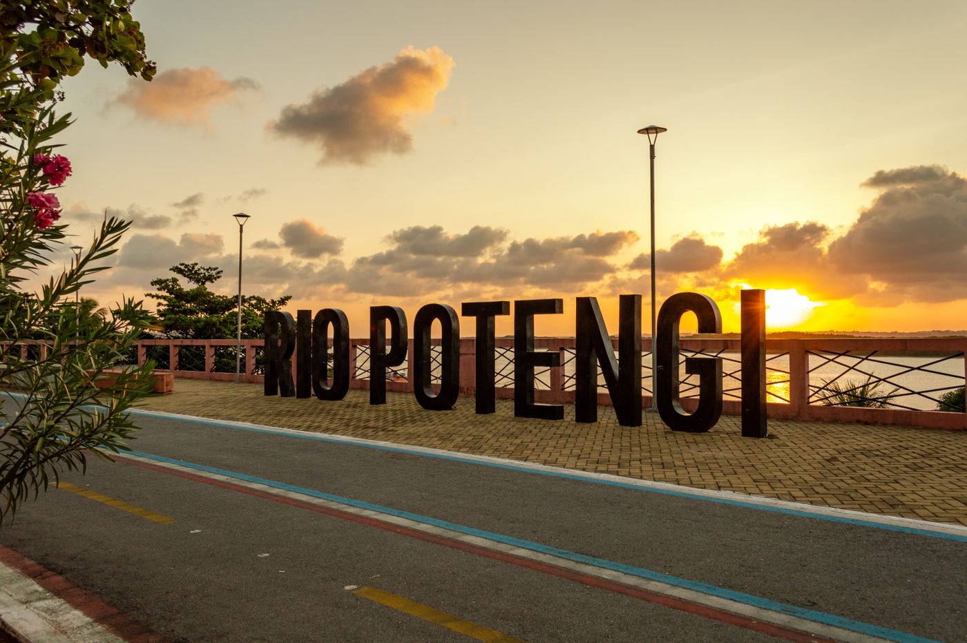 Placa com as letras RIO POTENGI em um mirante ao pôr do sol, com o rio ao fundo, na saída de Natal para a Zona Norte