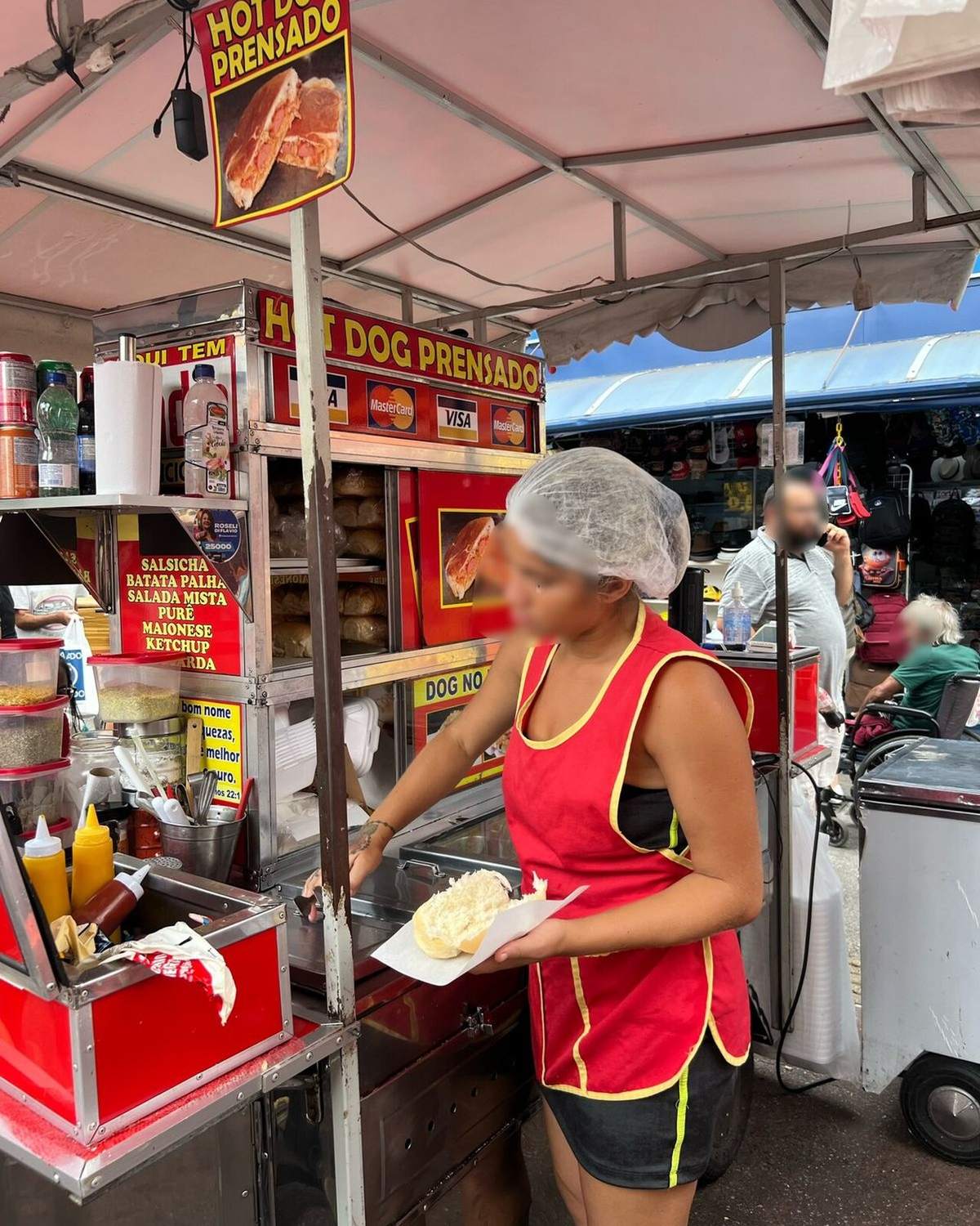 Mulher preparando um cachorro-quente numa barraquinha de rua em Osasco.