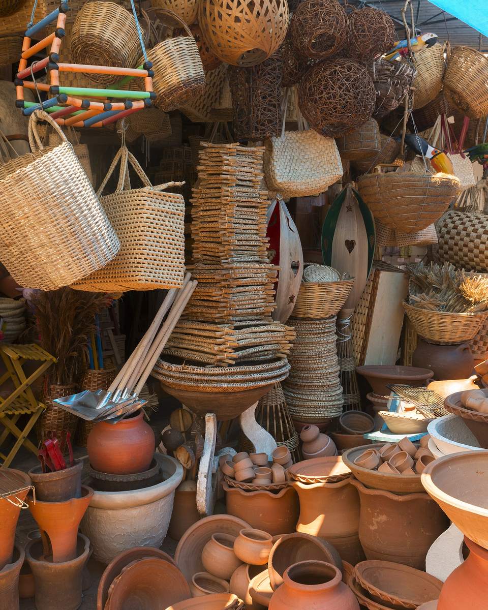 Cestaria de palha, bolsas trançadas e peças de cerâmica de barro em uma barraca de artesanato da Feira Central de Campina Grande