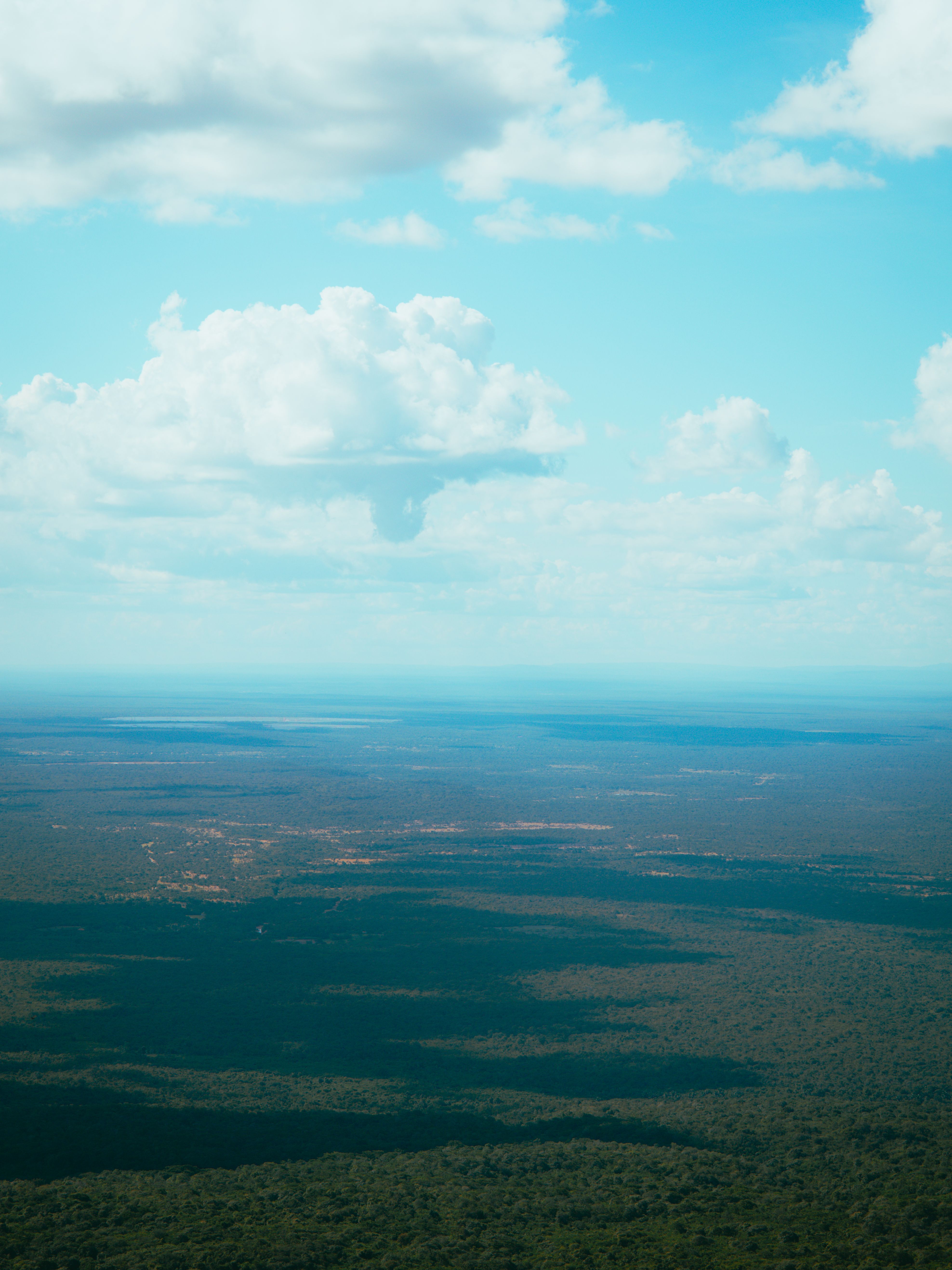 Vista aérea de colinas verdes cobertas de vegetação sob um céu com nuvens baixas, na região de Pedro II, no Piauí