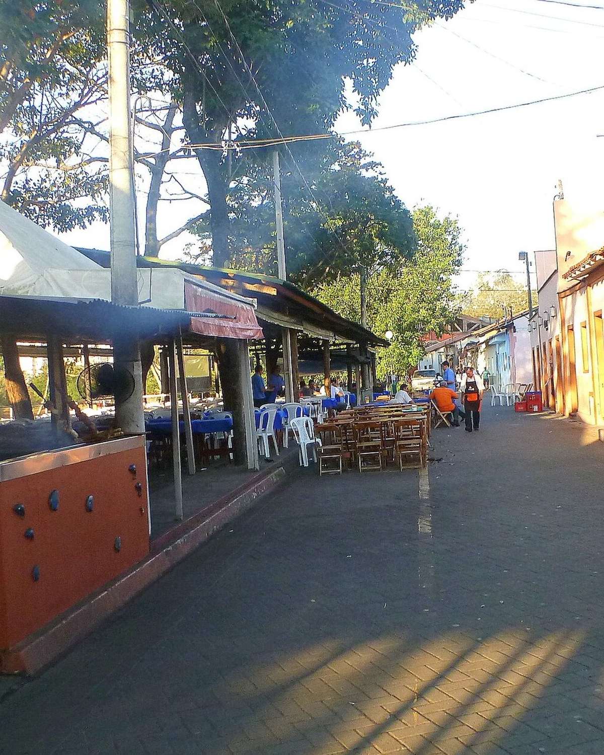 Mesas de restaurante à beira do rio na Rua do Porto, em Piracicaba, no fim da tarde.