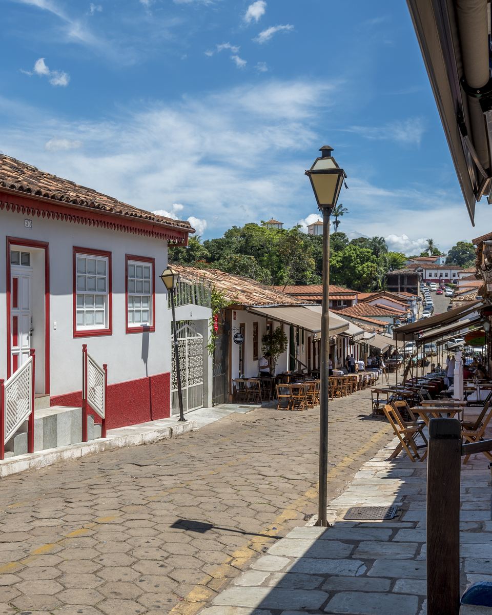 Rua de pedra do centro histórico de Pirenópolis com casas coloniais brancas de barra vermelha.