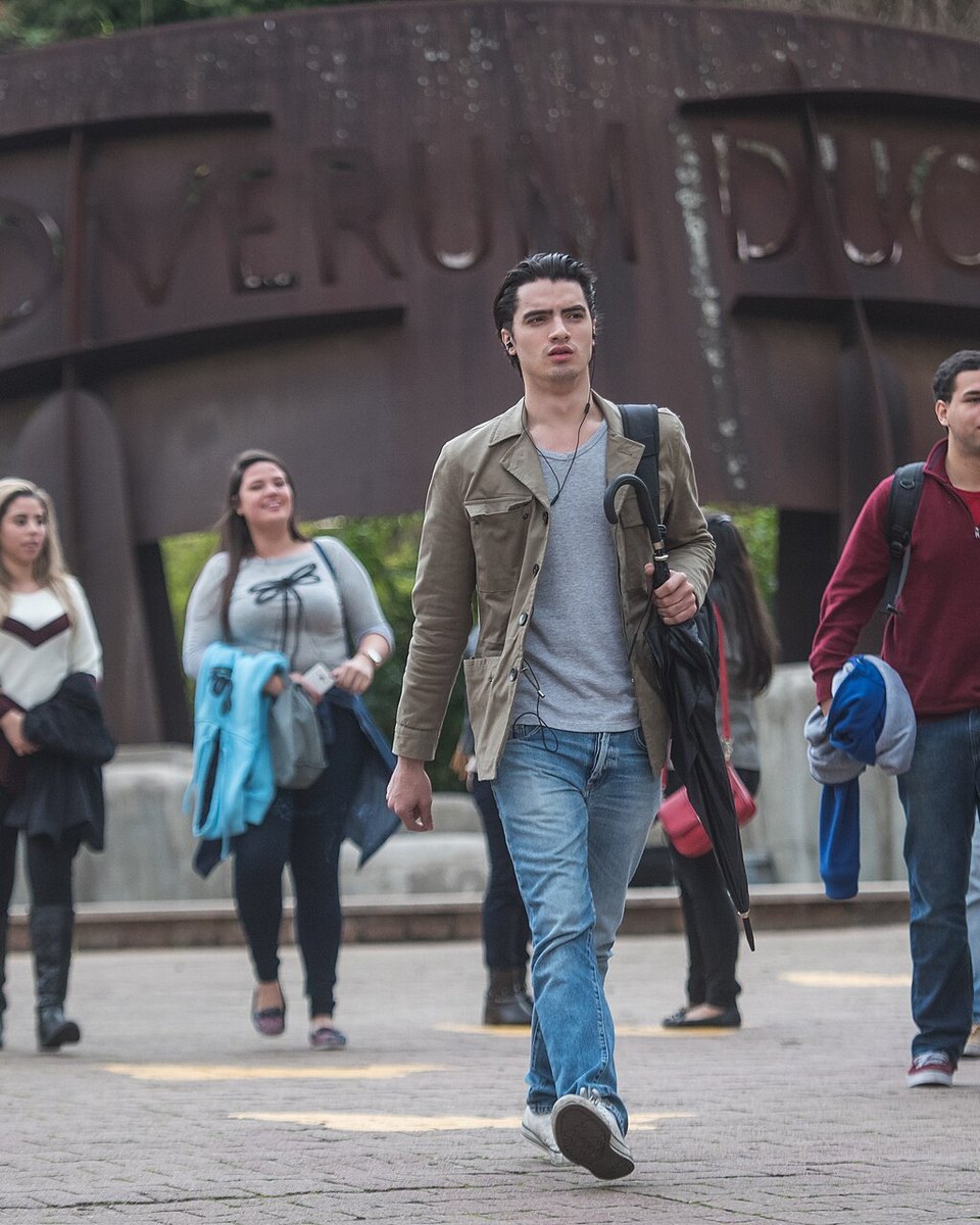Grupo de estudantes caminhando e conversando no campus da PUCRS, em Porto Alegre, na volta às aulas, com mochilas e casacos.