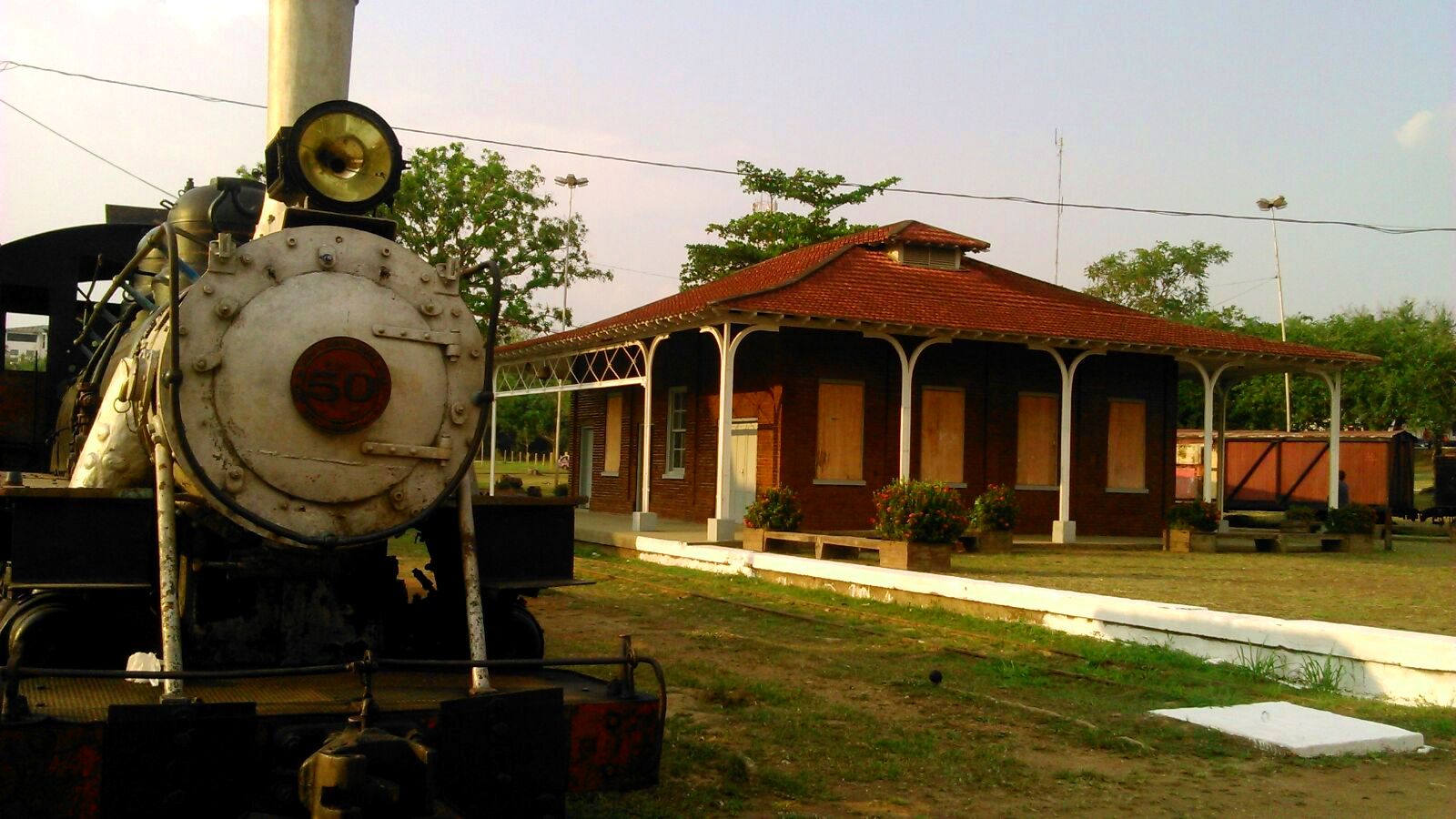 Locomotiva histórica e o prédio da estação da Estrada de Ferro Madeira-Mamoré, com telhado vermelho e varanda, em Porto Velho