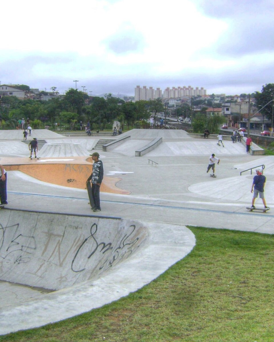 Jovens andando de skate numa pista de concreto ao ar livre no Jardim Ipanema, em Santo André, com casas e árvores ao fundo.