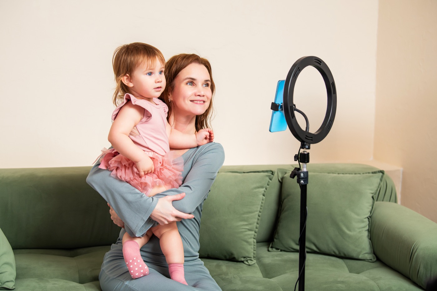 Mãe gravando um vídeo com a filha pequena e smartphone para uma marca de maternidade.